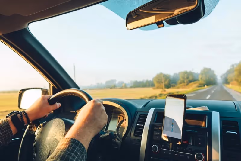 Conducteur sur une route de campagne avec un GPS affiché sur le tableau de bord pendant un road trip