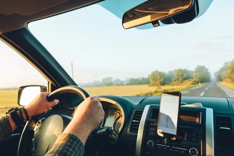 Conducteur sur une route de campagne avec un GPS affiché sur le tableau de bord pendant un road trip