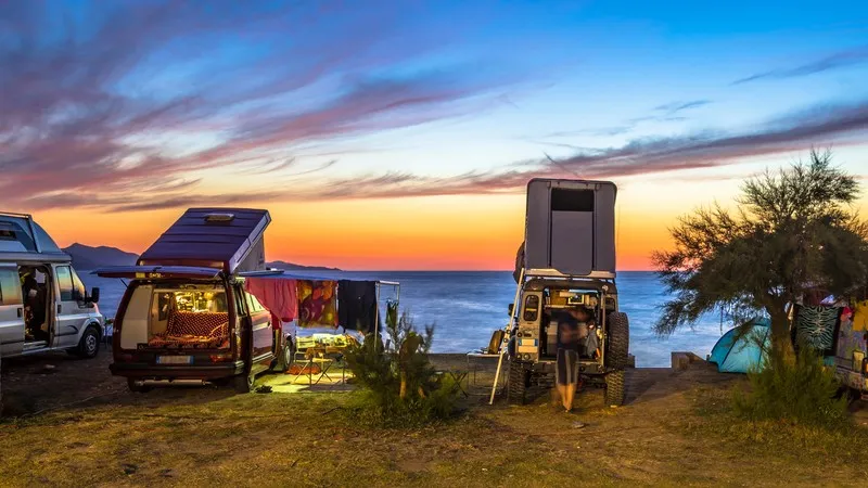 Vans aménagés stationnés en bord de mer au coucher du soleil, parfaits pour un road trip en liberté.