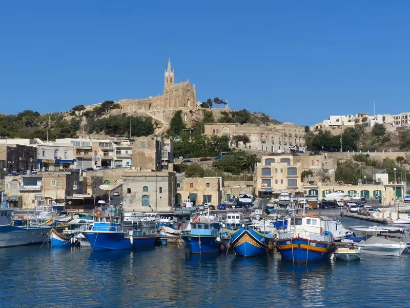 Port de Gozo avec ses bateaux colorés et l’église perchée sur la colline.