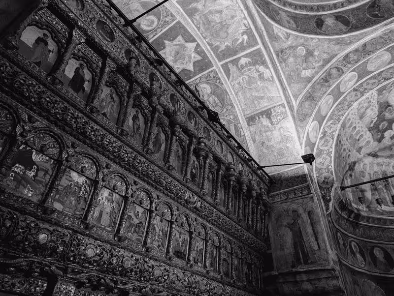 Intérieur de l’église Stavropoleos à Bucarest, iconostase orthodoxe richement sculptée et fresques religieuses.