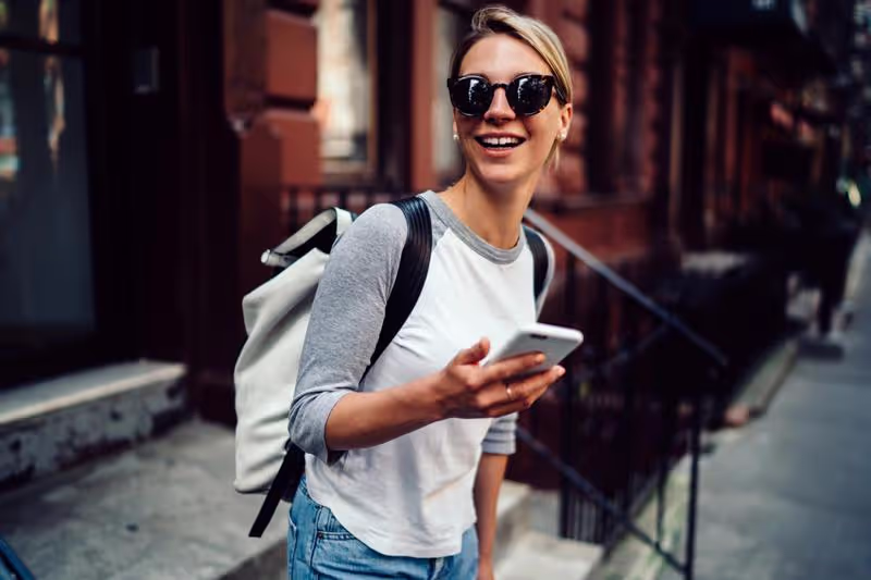 Femme souriante à Brooklyn tenant un téléphone dans sa main connecté avec une esim