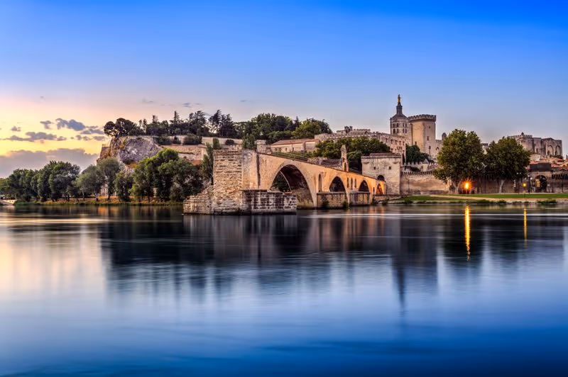 Pont d’Avignon et Palais des Papes au coucher du soleil avec reflets sur le Rhône