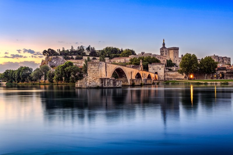 Pont d’Avignon et Palais des Papes au coucher du soleil avec reflets sur le Rhône