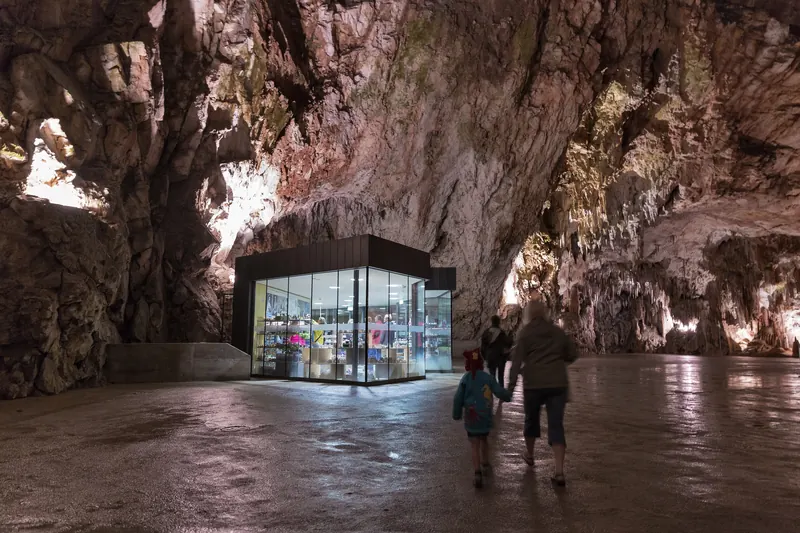 Immense salle souterraine des grottes de Postojna avec stalactites et visiteurs devant le pavillon vitré, Slovénie