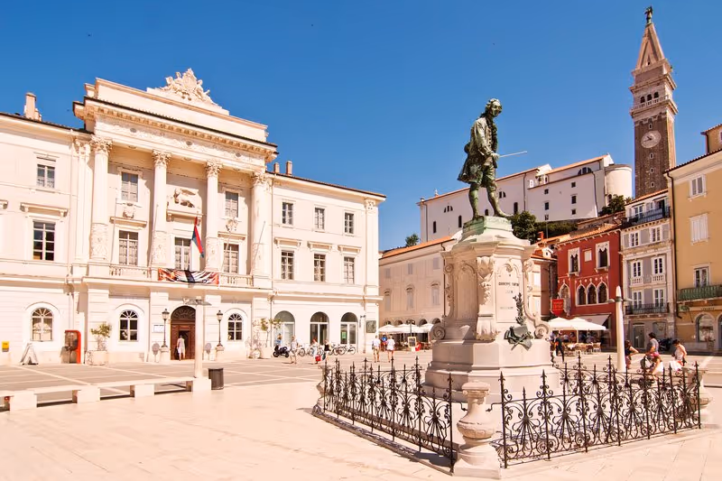 Place Tartini à Piran en plein soleil avec la statue de Giuseppe Tartini, l'hôtel de ville et le clocher de l'église Saint-Georges