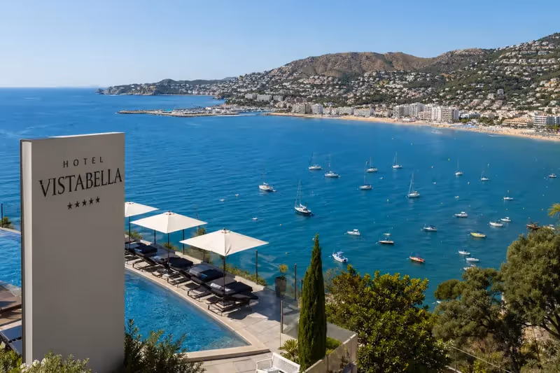 Vue panoramique depuis l’Hotel Vistabella à Roses sur la Costa Brava avec piscine, mer Méditerranée et bateaux dans la baie.