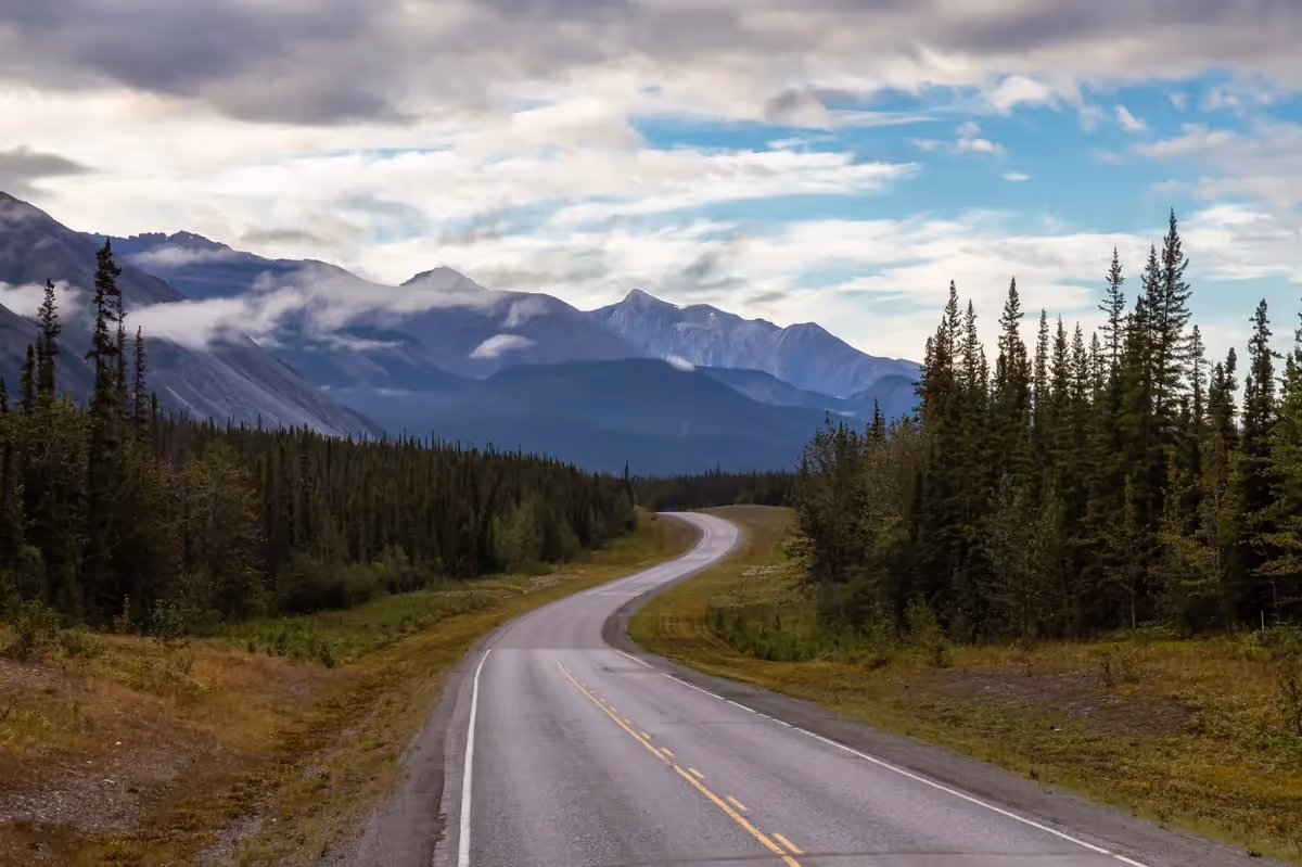 Route traversant les montagnes sauvages du Canada au milieu des forêts de conifères pendant un road trip.