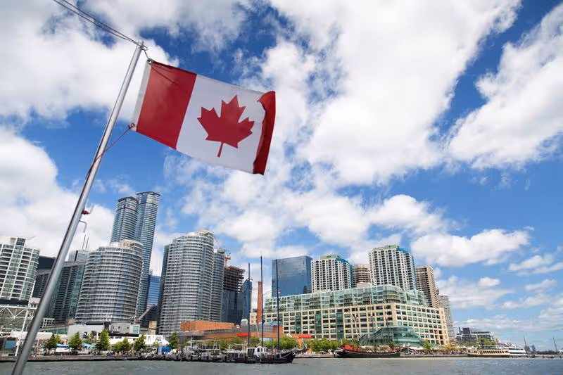 Drapeau canadien devant le skyline de Toronto depuis le lac Ontario — étape clé d'un séjour au Canada sur mesure