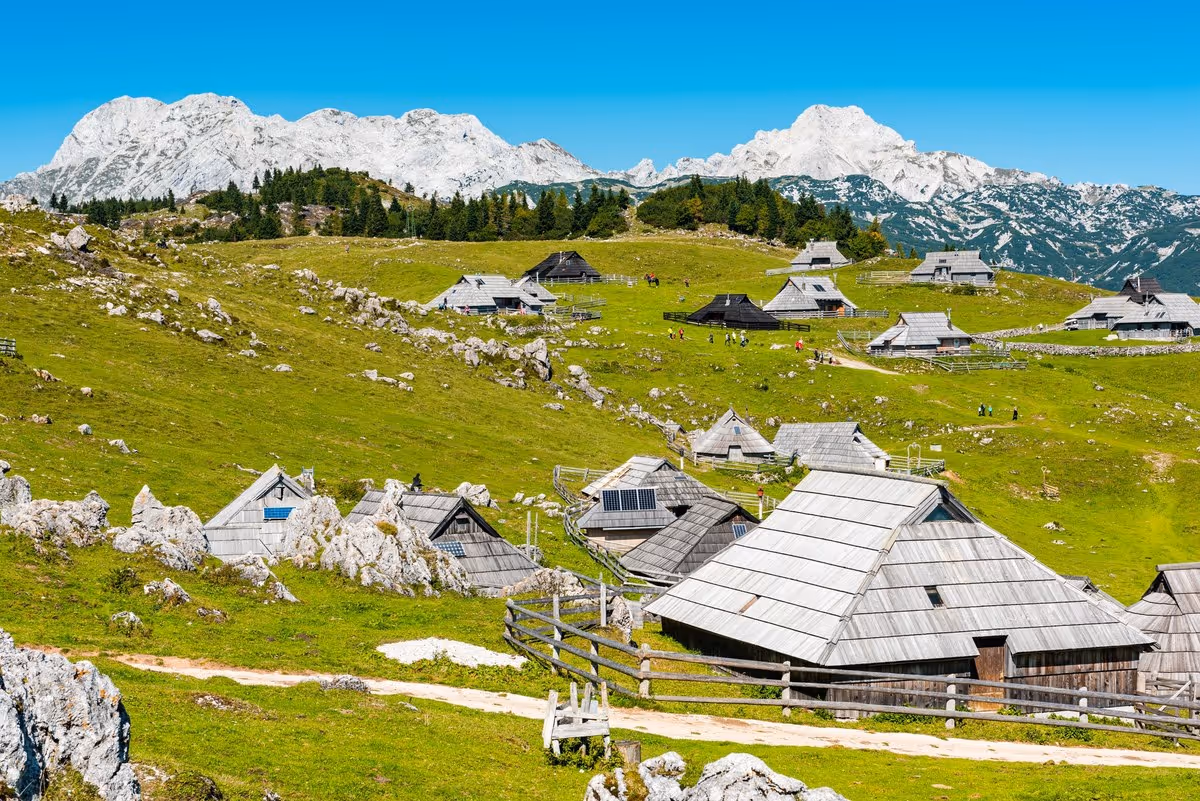 Vue des chalets traditionnels de Velika Planina en Slovénie avec les Alpes slovènes en arrière-plan.