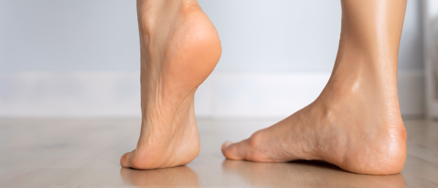 Close-up of feet with one heel raised, demonstrating a common movement pattern linked to posterior tibial tendinopathy and flatfoot-related pain.