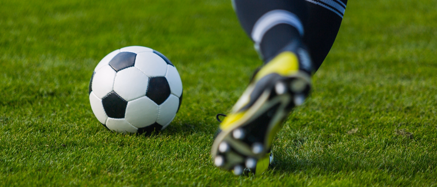 Soccer player about to kick ball on grass field, illustrating risk of eversion ankle sprain from outward ankle rolling during sports activity.