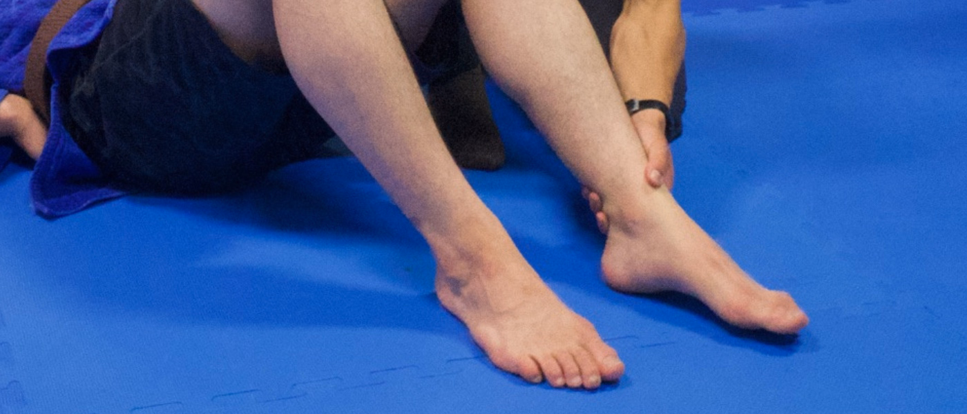Physiotherapist assessing foot and ankle mobility in a patient, focusing on the forefoot and first metatarsophalangeal joint, commonly involved in sesamoiditis. Image illustrates clinical evaluation used in physiotherapy management of sesamoid pain.
