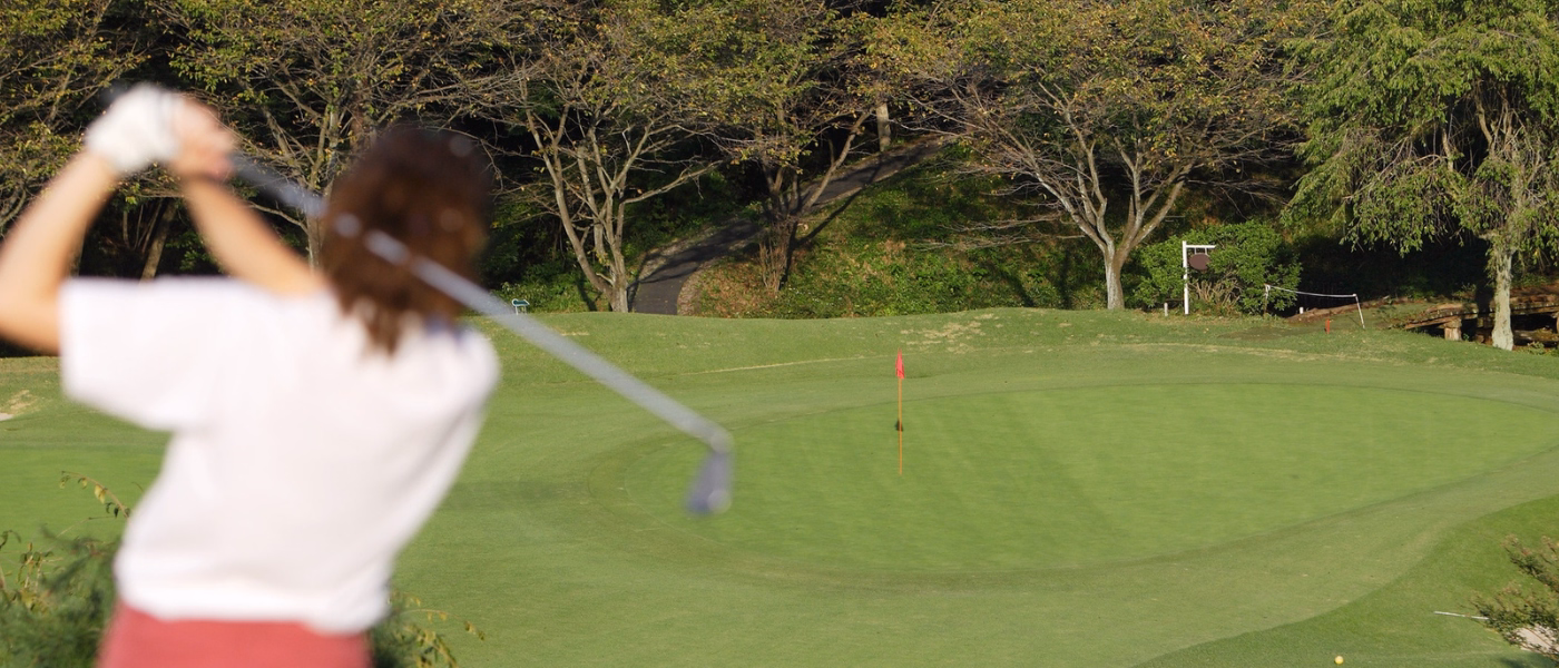 Golfer swinging a club on a golf course illustrating non specific low back pain during rotational sports activities