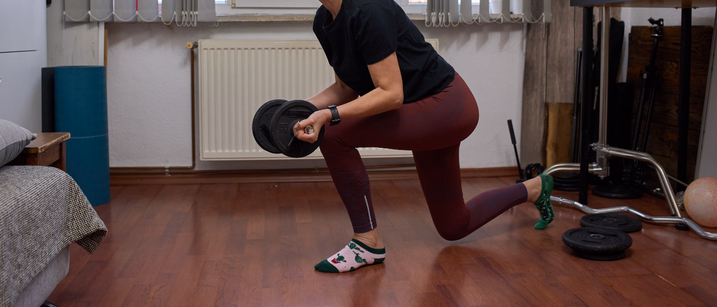 Athlete performing weighted lunge exercise commonly used in quadriceps tendinopathy rehabilitation