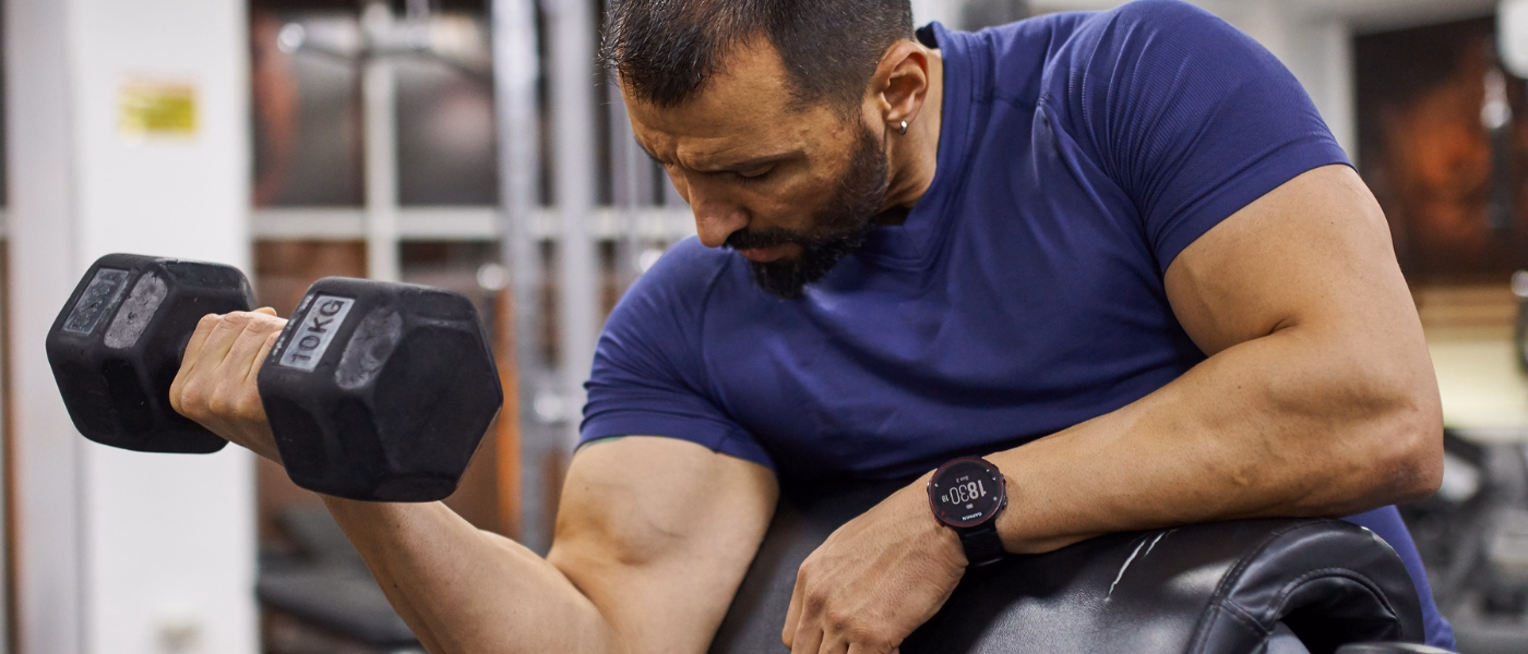 Athlete performing dumbbell biceps curl exercise related to biceps strain or rupture rehabilitation