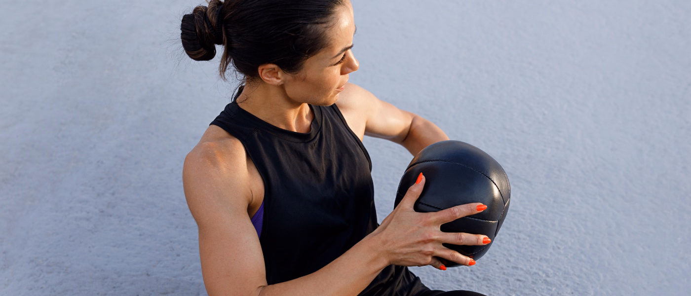 Woman performing core stability exercise with medicine ball for lumbar instability rehabilitation
