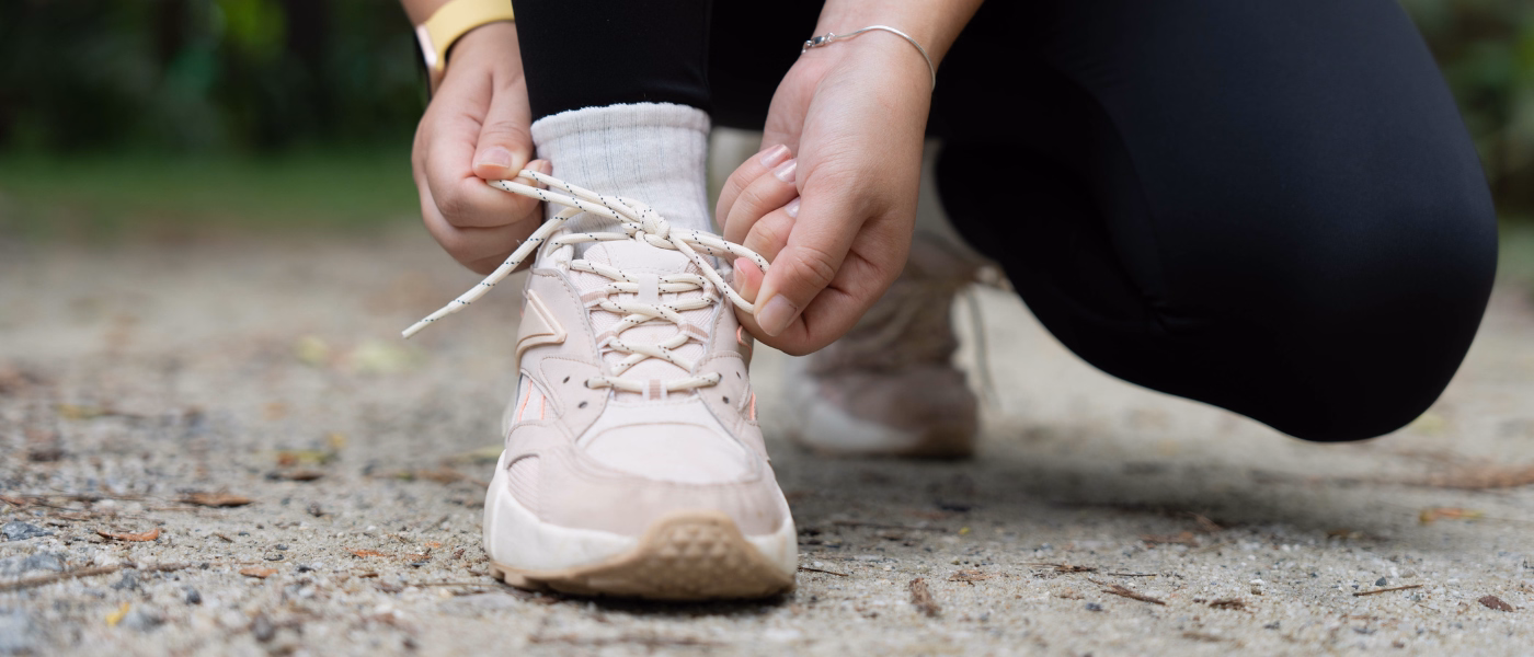 Person tying running shoe before exercise illustrating lumbar muscle strains and sprains in active individuals