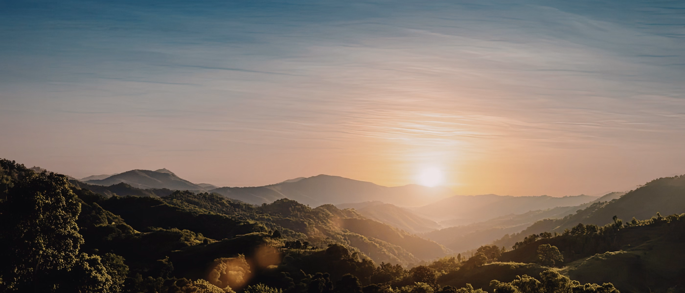 Sunrise over rolling green hills and mountains, symbolizing a hopeful recovery journey and regained confidence after post-prostatectomy incontinence.