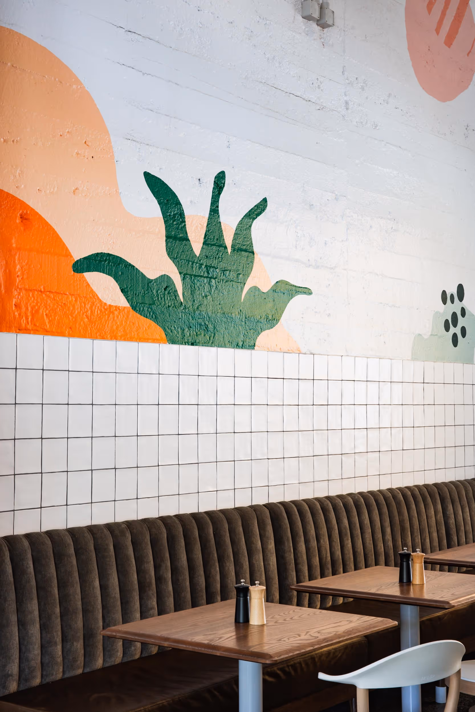 Abstract mural above tiled walls and brown bench seating in the interior of the Auckland Zoo Elephant House