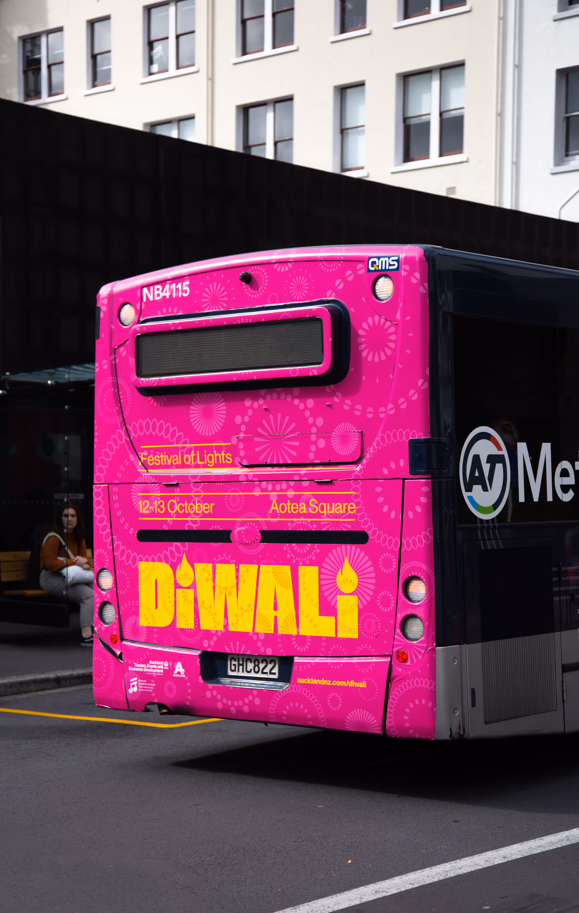 Vibrant pink bus back advertisement for the Auckland Diwali Festival featuring rangoli and fireworks motifs designed by Blink