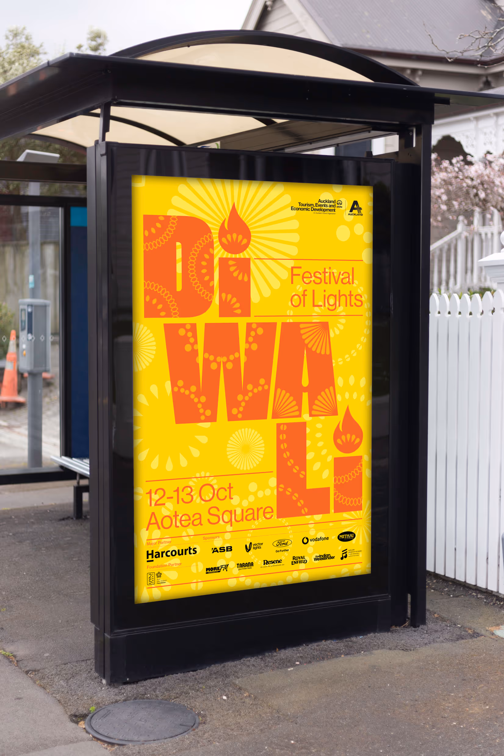 Bright yellow and orange bus shelter poster for the Auckland Diwali Festival, featuring rangoli-inspired typography and event details for 12-13 Oct at Aotea Square.