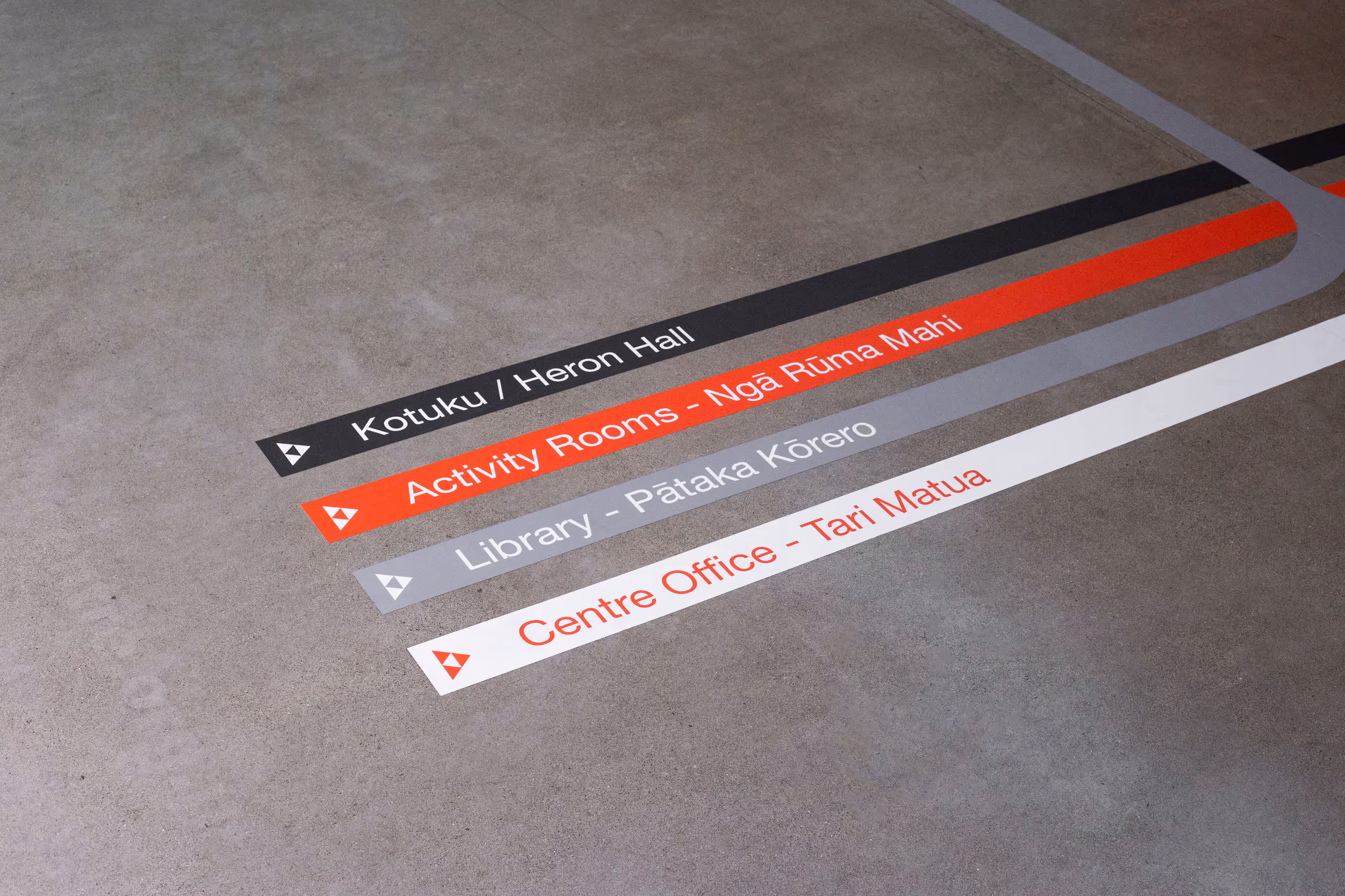 Auckland Council community centre floor wayfinding vinyl close-up with bilingual te reo Māori and English signage, designed, fabricated and installed by Blink, Auckland