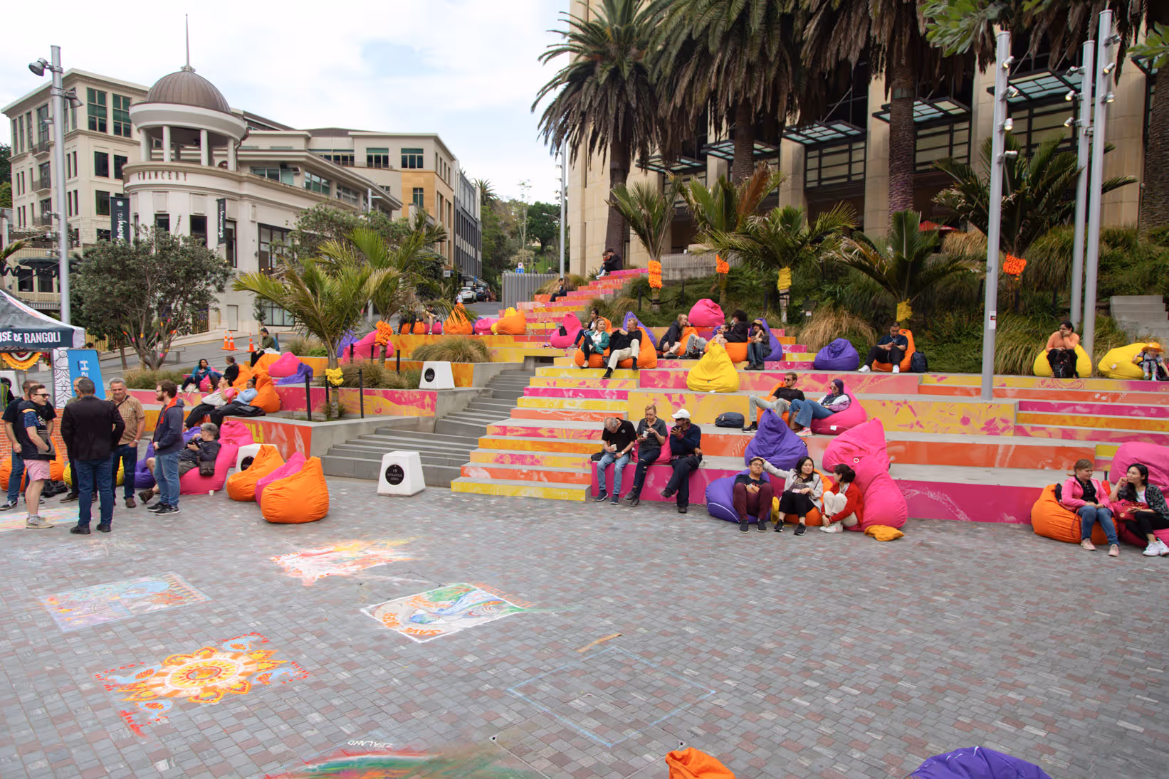 People enjoying colourful beanbag seating and chalk artwork in Aotea Square during the Auckland Diwali festival.