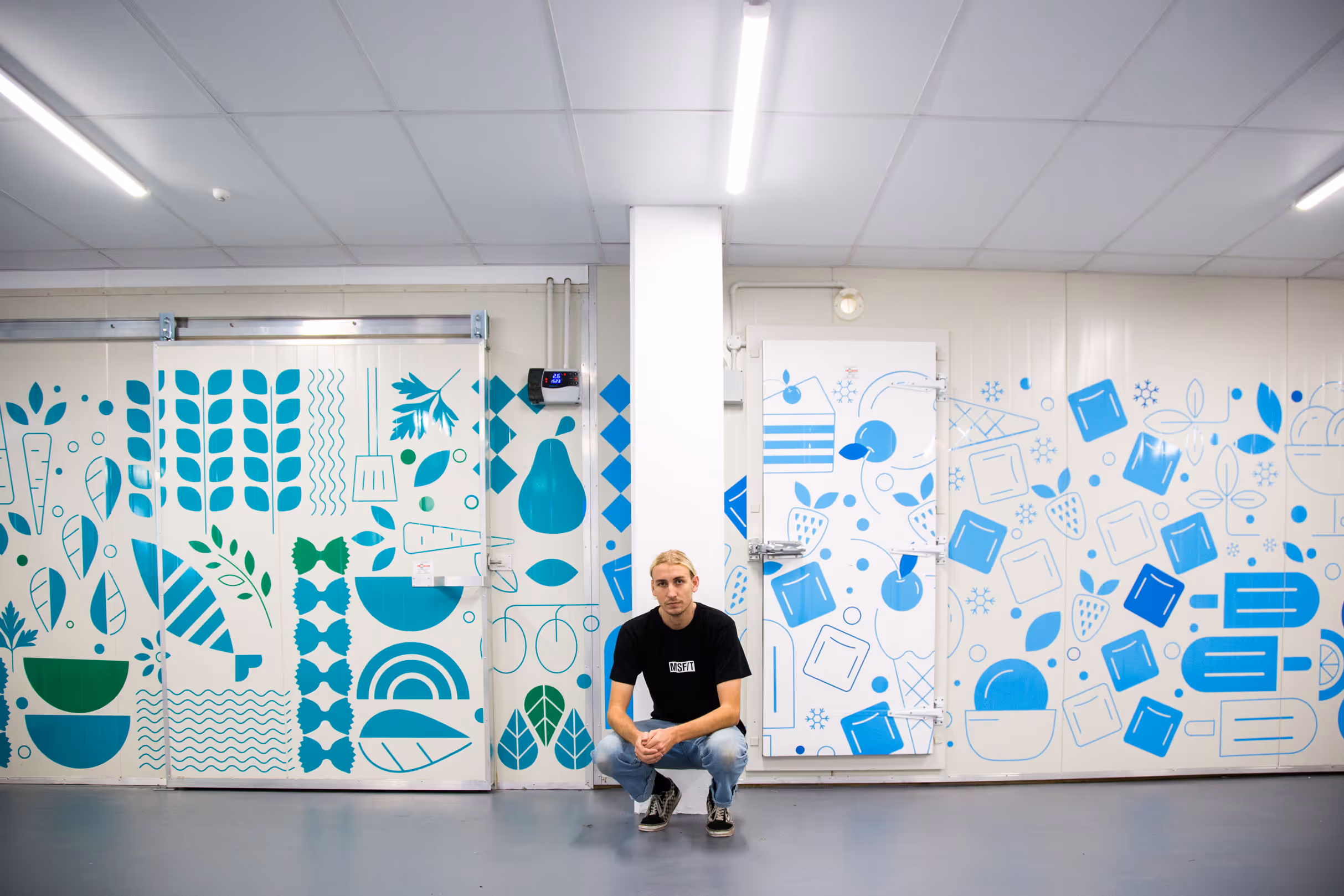 Custom vibrant green and blue wall and door decals featuring abstract food iconography on walk-in chillers for Collective workspace by Blink