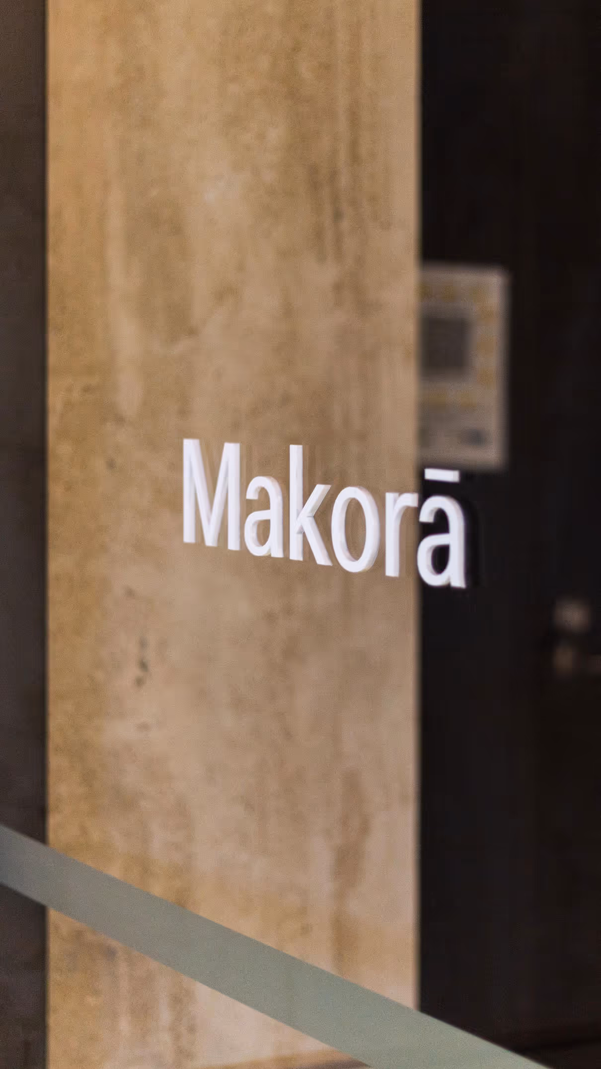 Meeting room signage for PwC, featuring the word 'Makorā' in white lettering applied to a glass surface