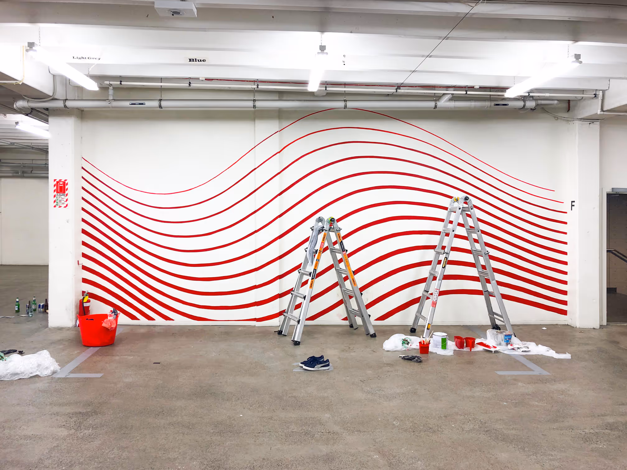 Red Bull office mural in Auckland by Blink, featuring red, wavy lines painted on a white wall