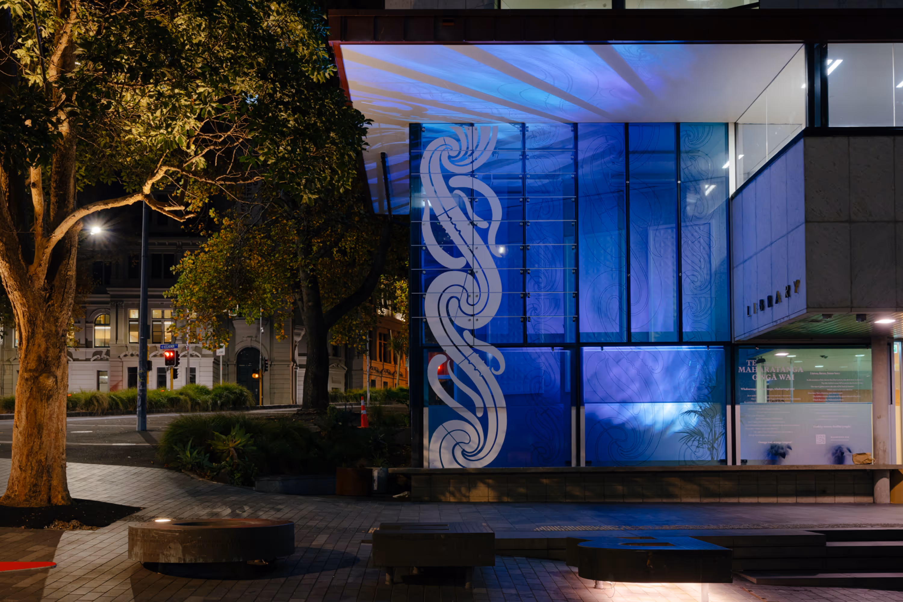 Te Maharatanga o Ngā Wai glass vinyl installation at night with blue lighting at Tāmaki Pātaka Kōrero Central Library, designed, fabricated and installed by Blink, Auckland