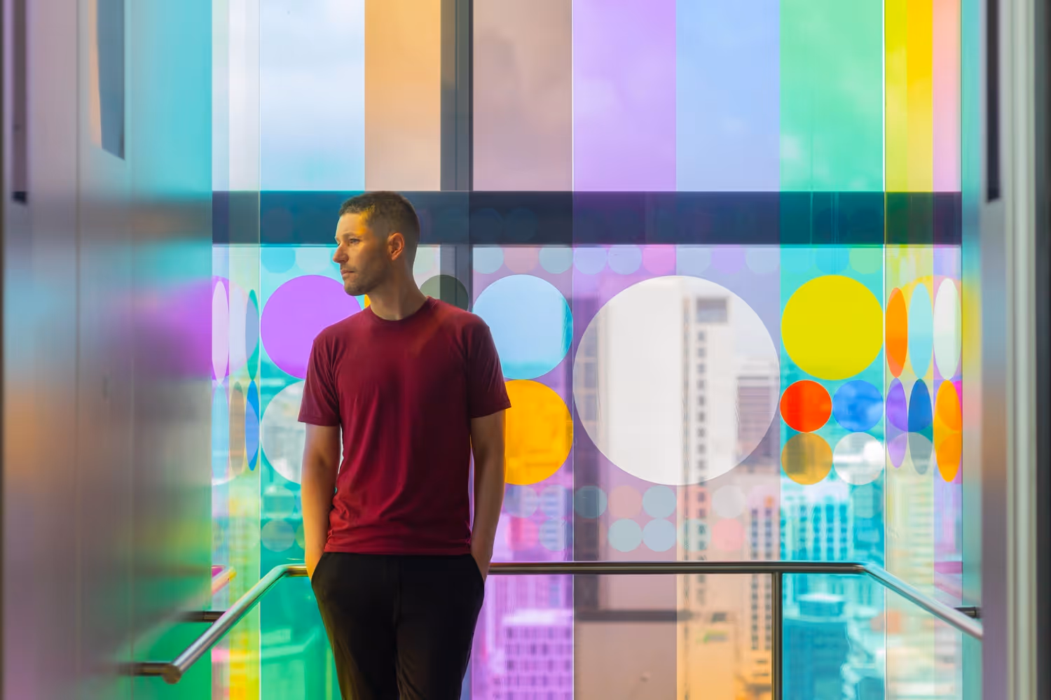 Person standing in front of colourful geometric glass vinyl installation at Commercial Bay, designed, fabricated and installed by Blink, Auckland