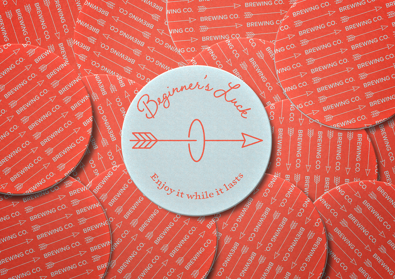 Round beer coasters with a red background and white arrow patterns, featuring one white coaster in the center labeled 'Beginner's Luck' with an arrow and the phrase 'Enjoy it while it lasts.'