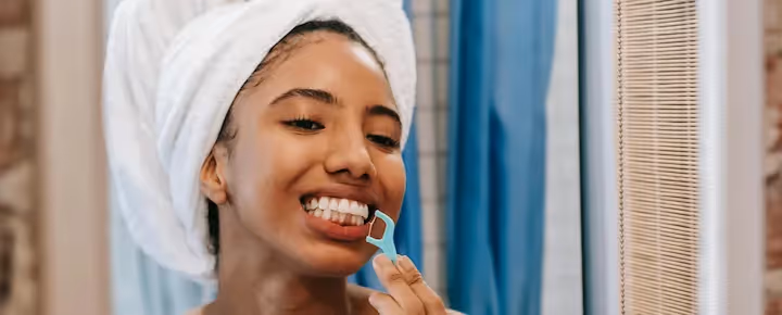 Woman flossing her teeth in bathroom with.
