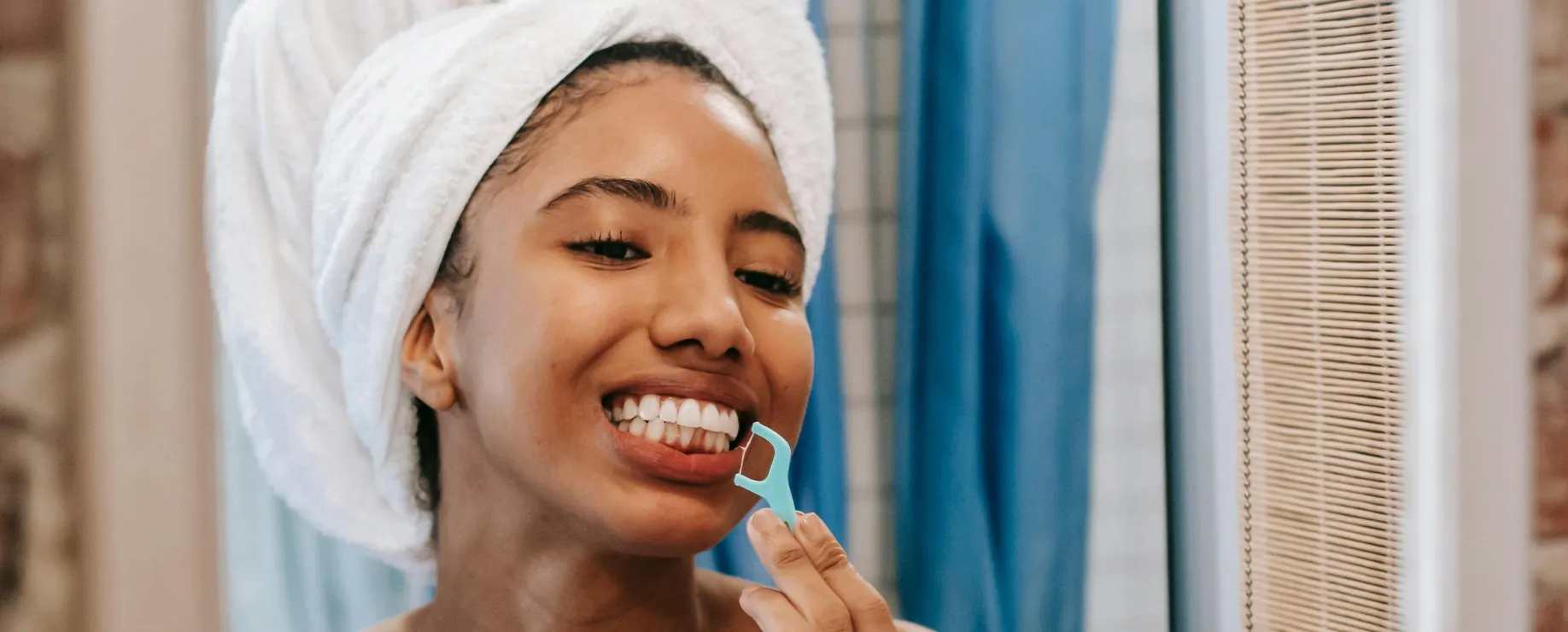 Woman flossing her teeth in bathroom with.