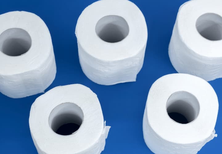 Four Rolls Of Toilet Paper Sitting On A Blue Surface.