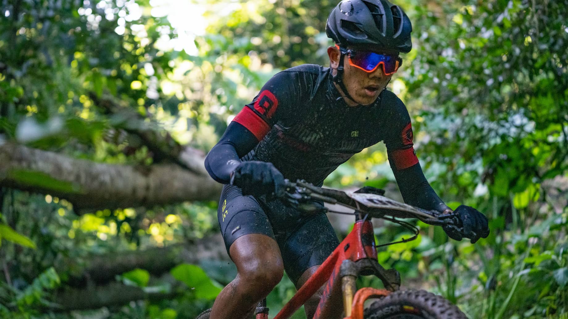 A Man Riding A Green Bike Through A Forest