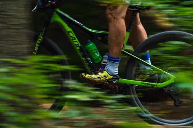 A Man Riding A Green Bike Through A Forest