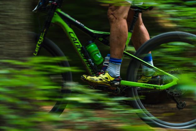 A Man Riding A Green Bike Through A Forest