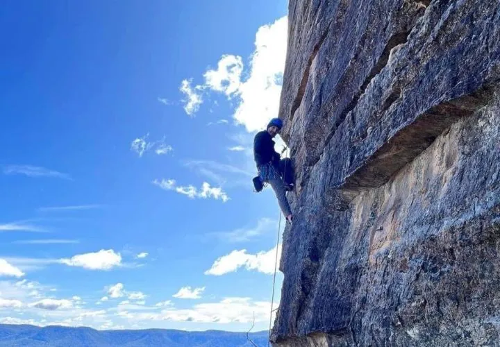 A Person Climbing Up The Side Of A Mountain.