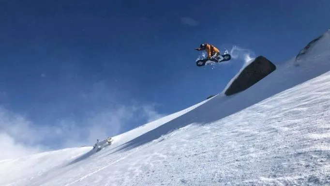 A Man Flying Through The Air While Riding A Snowboard