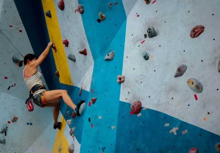 A Person Climbing Up The Side Of A Climbing Wall