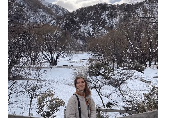 A Woman Standing In The Snow In Front Of A Mountain