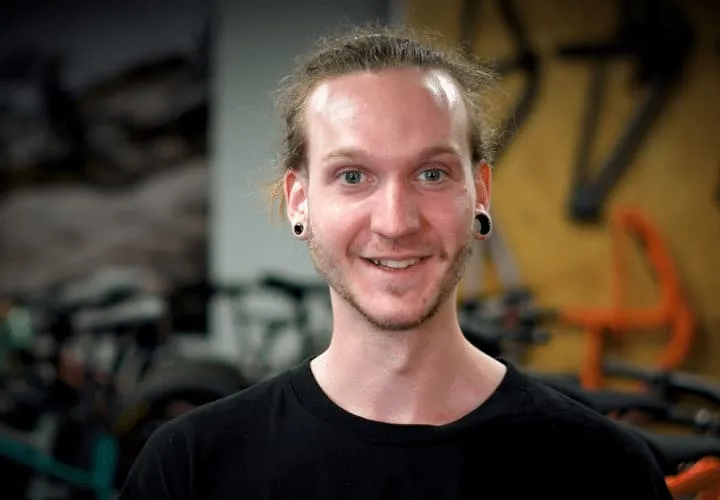 A Man In A Black Shirt Smiling At The Camera