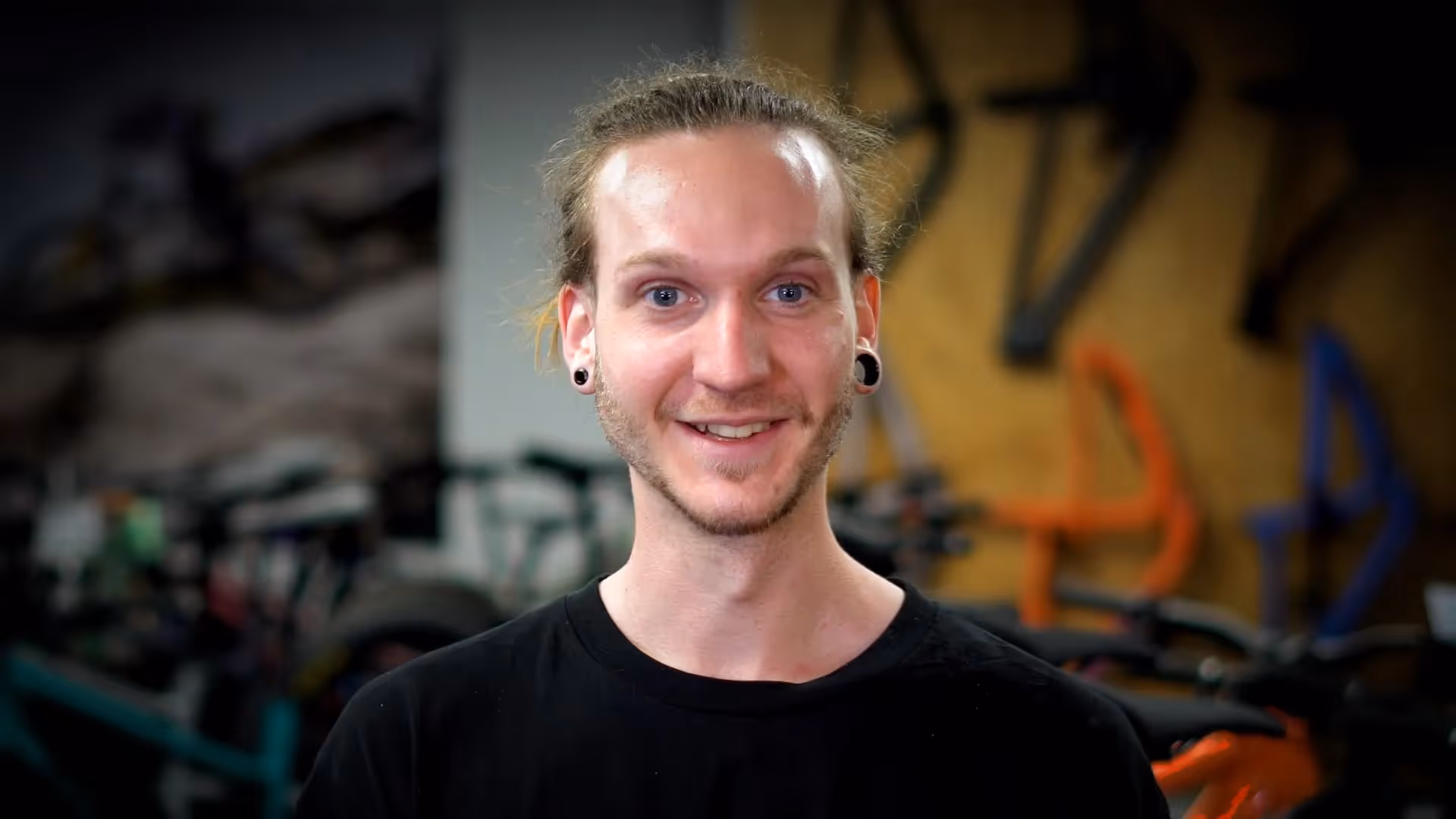 A Man In A Black Shirt Smiling At The Camera