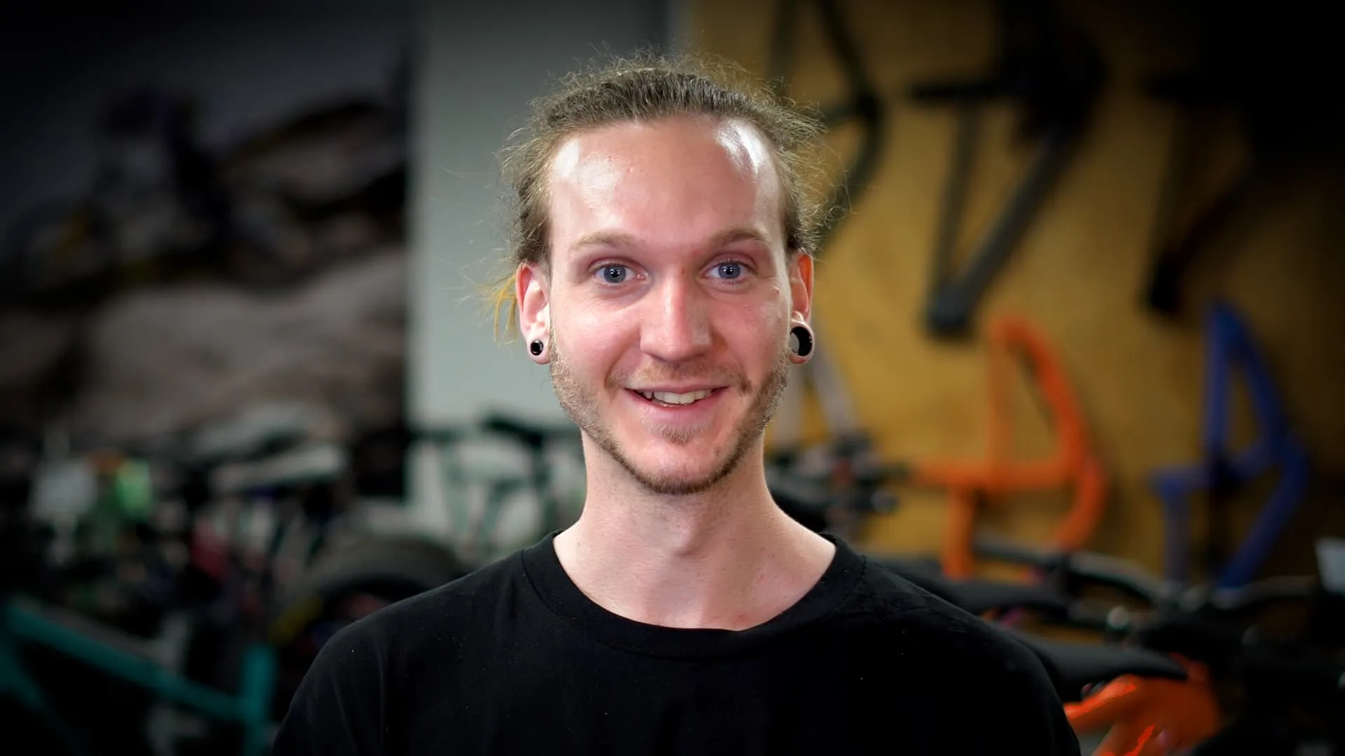 A Man In A Black Shirt Smiling At The Camera