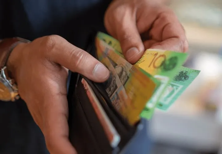 A Person Holding A Wallet With Money Sticking Out Of It