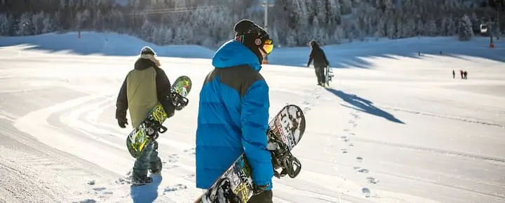 People with snowboards heading to the slope