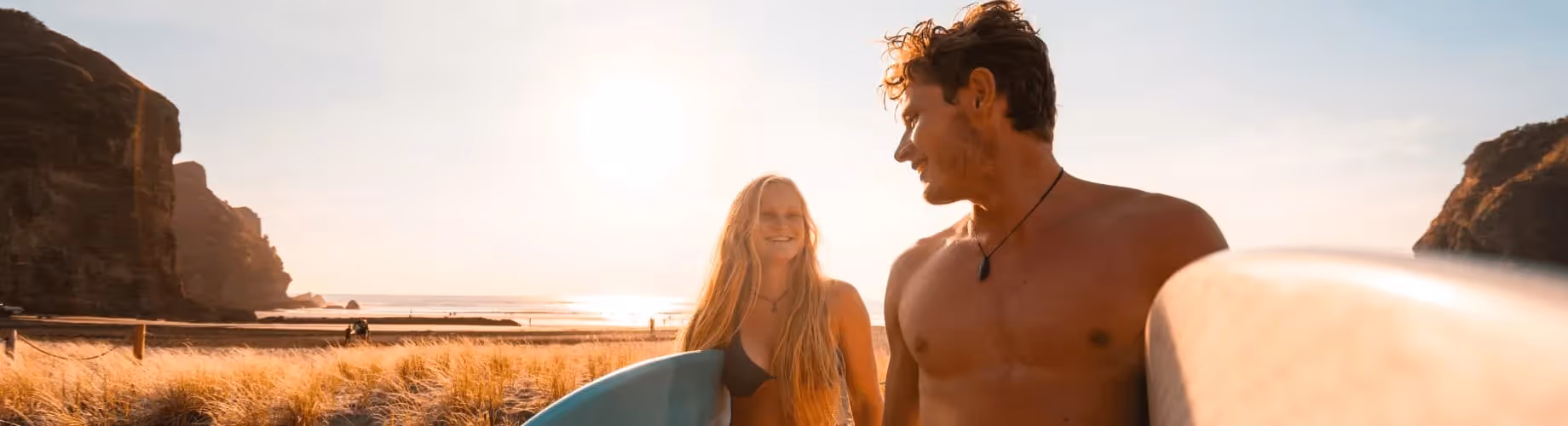 A Man And A Woman Holding Surfboards On A Beach